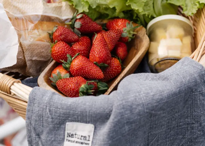 A basket of strawberries and other food items. The strawberries are red and juicy. There are also blueberries, raspberries, and blackberries in the basket. There is a towel on the bottom of the basket to protect the food