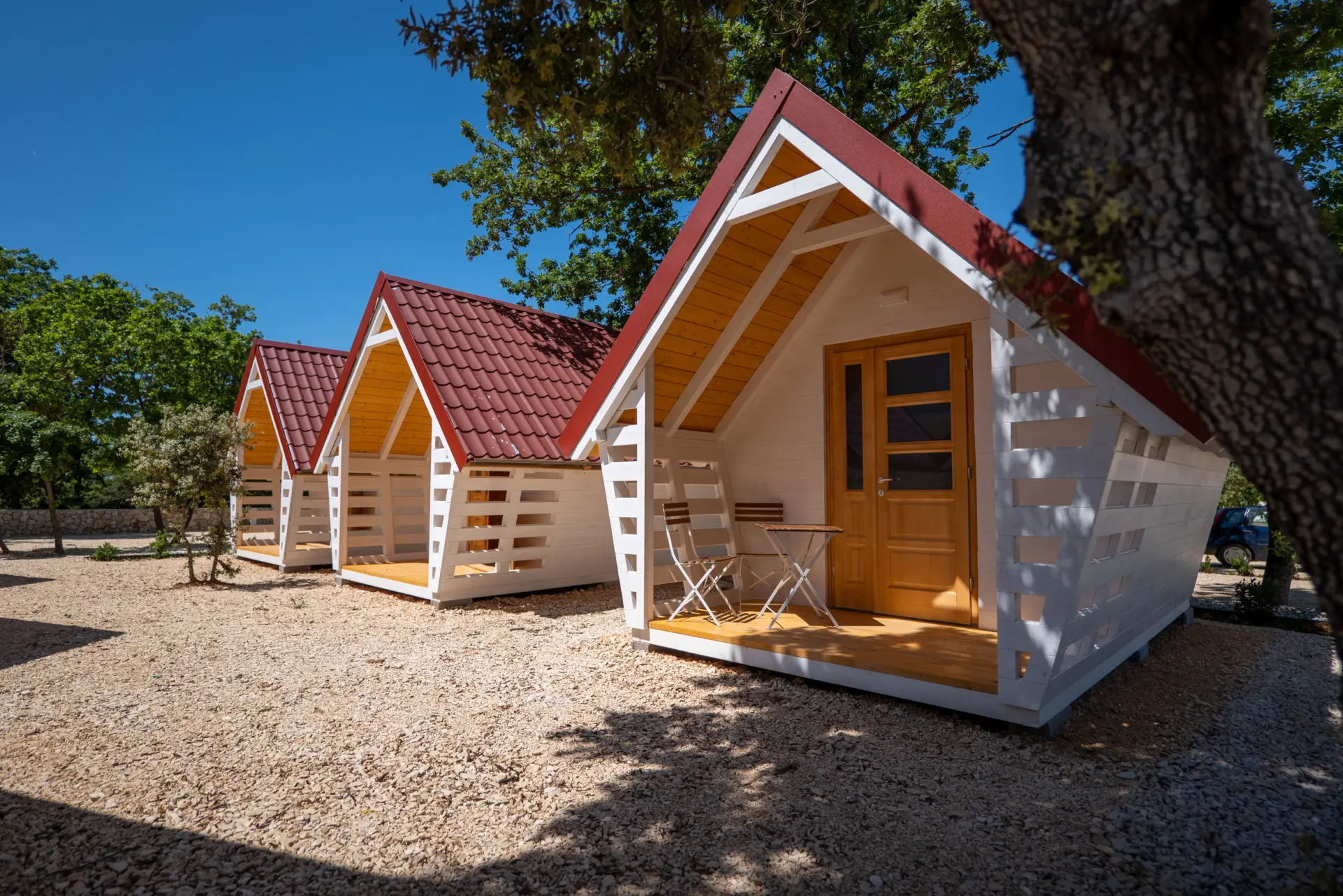 Row of 3 glamping huts with terrasses under oak trees