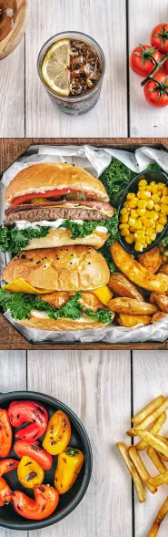 A wooden tray filled with food. The food includes hamburgers, french fries, corn, and vegetables. The hamburgers are on buns and there are toppings like lettuce, tomato, and cheese. The french fries are golden brown and crispy. The corn is grilled and the vegetables are a variety of colors