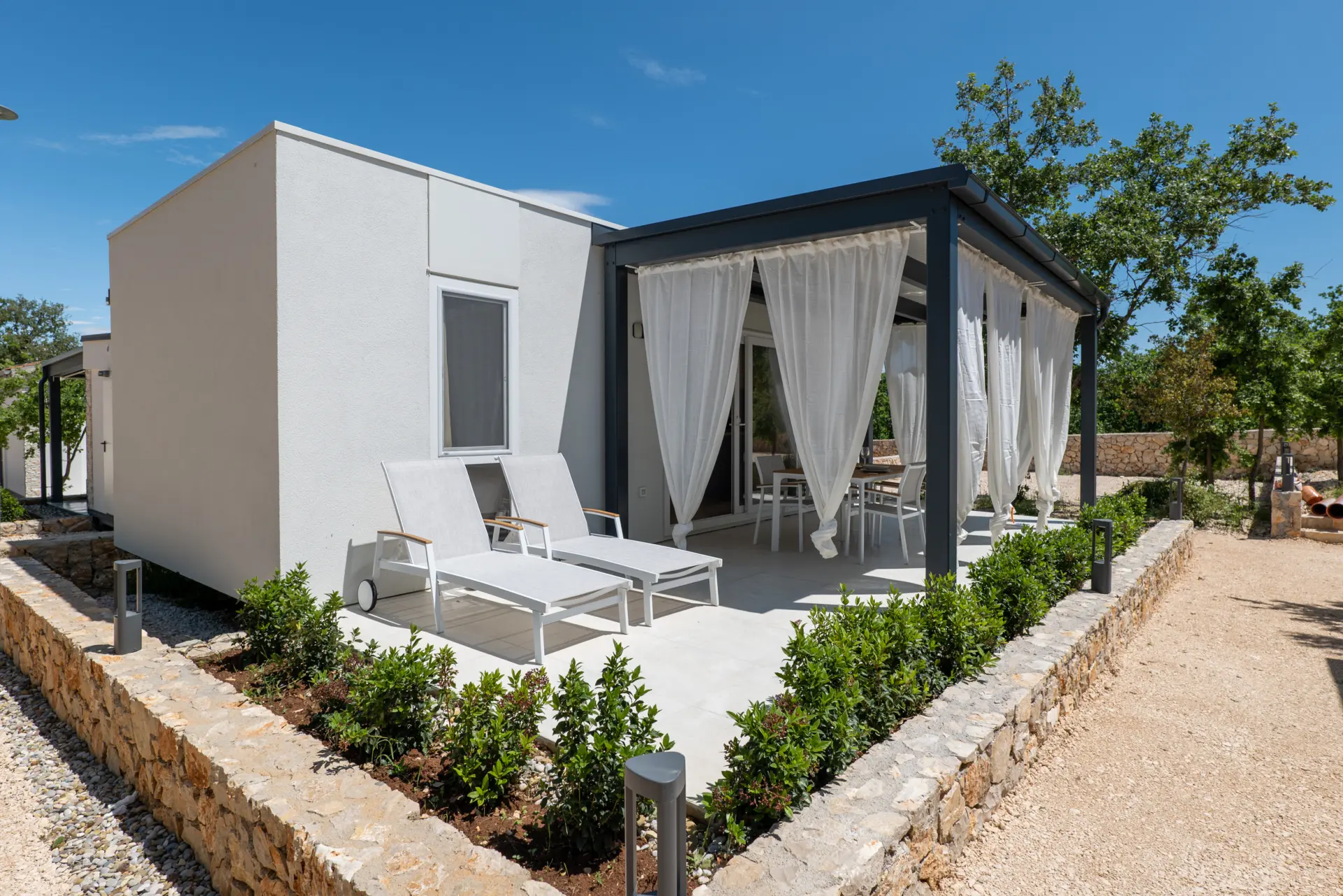 Mobile home terrasse covered in white curtains next to a tree