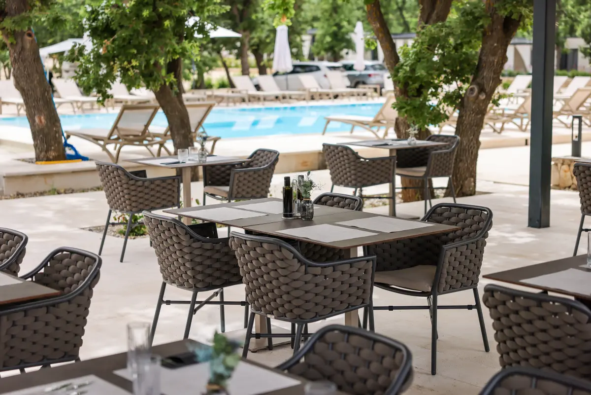 Restoran in Dionis Campingu Zaton mit Tischen und Pool im Hintergrund